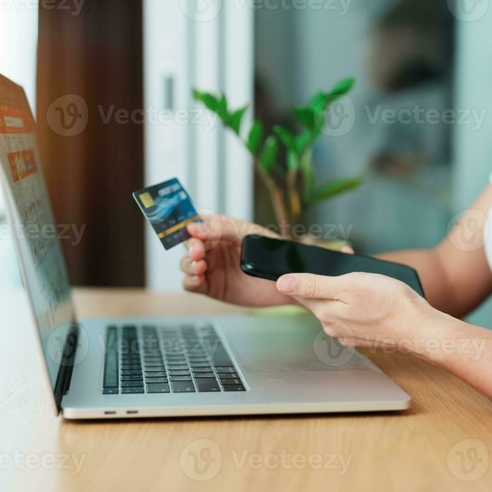 woman hand holding credit card and using laptop with mobile phone for online shopping while making order. Marketplace platform website, technology, ecommerce, digital banking and online payment photo