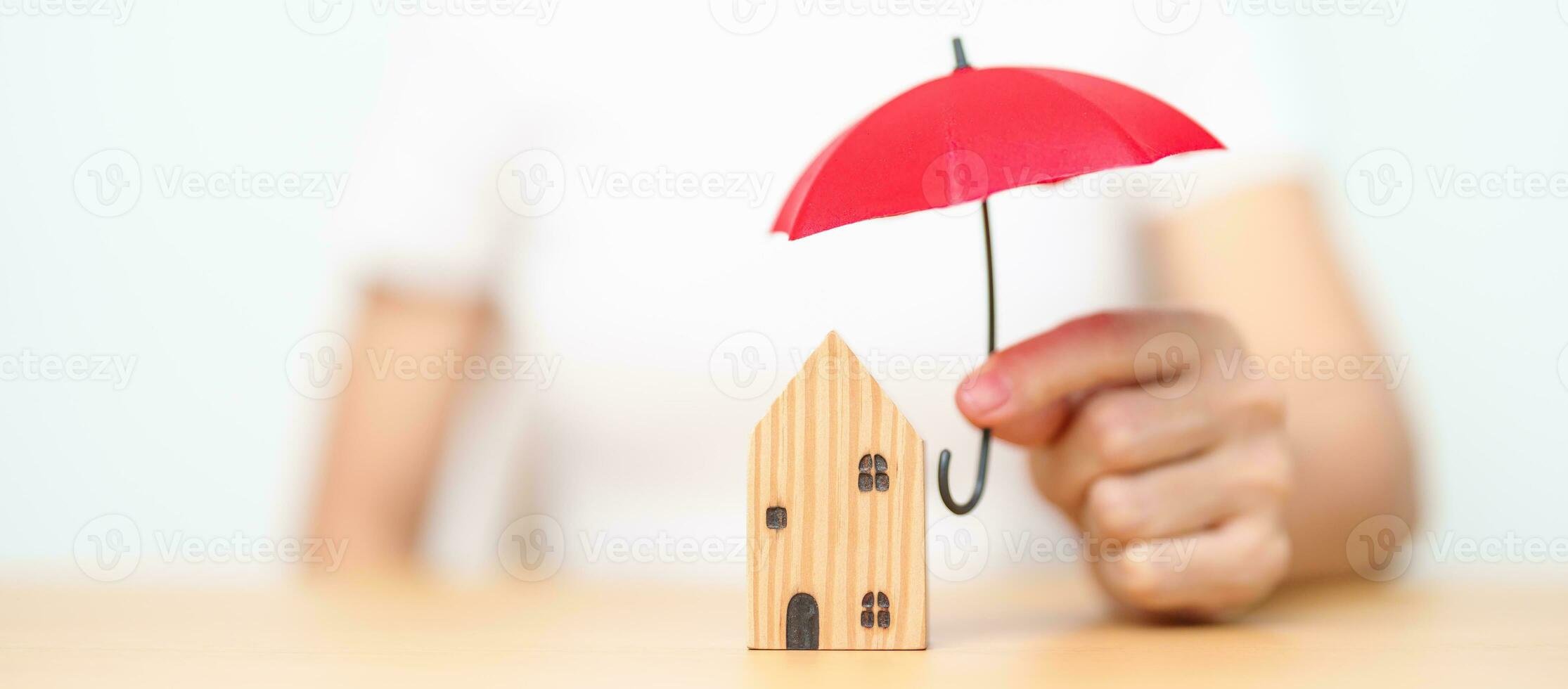 mujer de negocios mano sosteniendo paraguas rojo cubierta modelo de casa de madera. conceptos inmobiliarios, de seguros y de propiedad foto