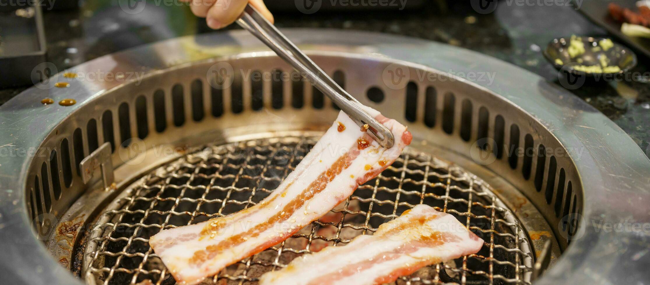 Hand Grilling meat pork on stove serve in restaurant. Japanese food and Korean BBQ traditional style photo