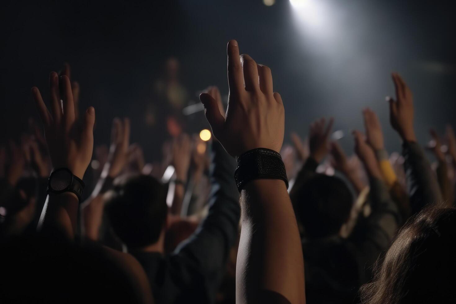 The crowd at a concert in front of the stage with hands raised up, Peoples closeup rear view raising their hands, photo