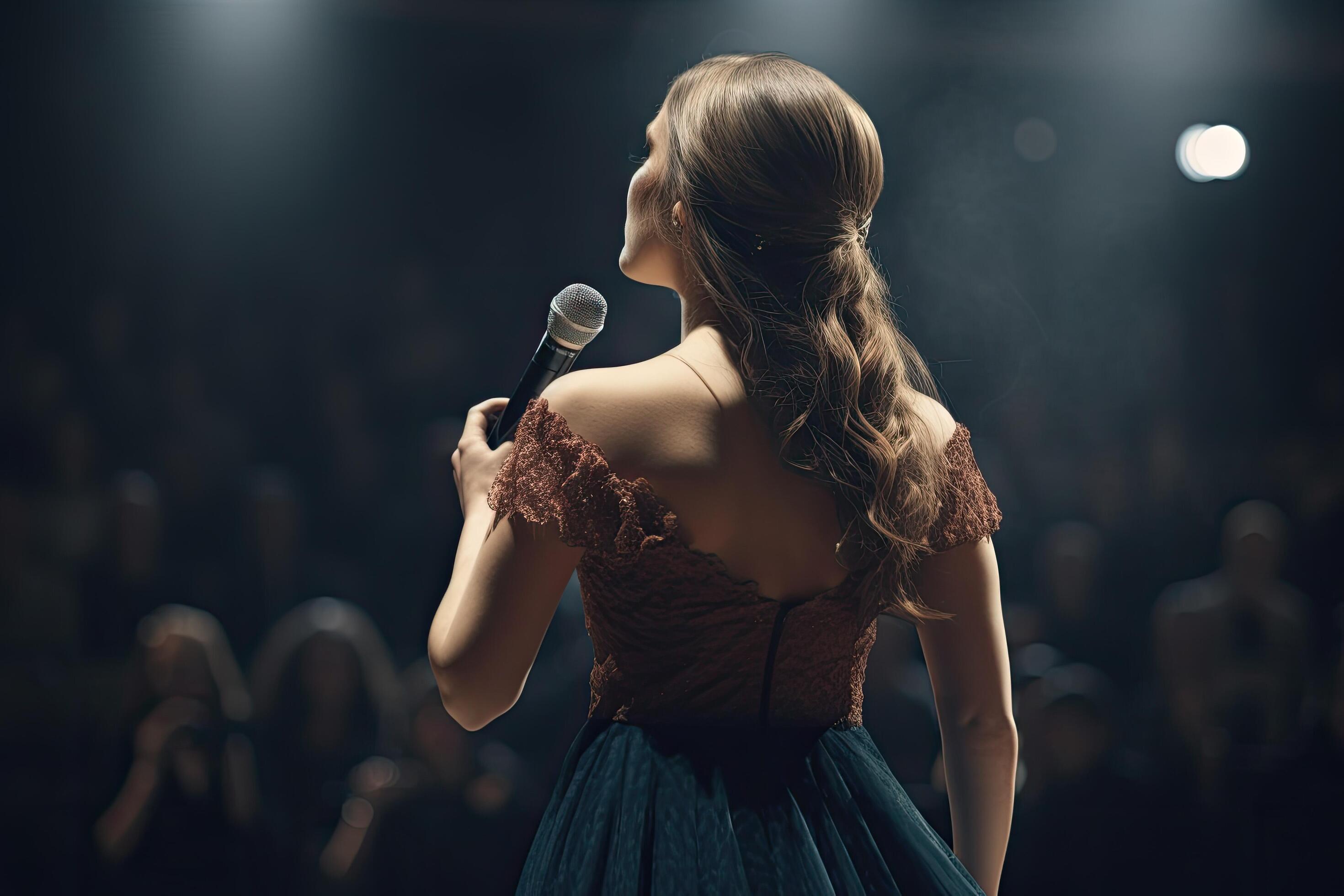 Beautiful young woman singing into a microphone on a dark background
