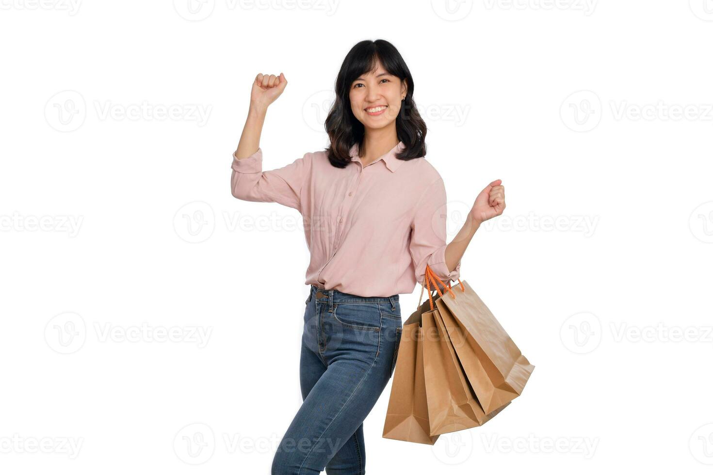 joven contento asiático mujer con casual camisa y mezclilla pantalones participación compras papel bolso aislado en blanco antecedentes foto