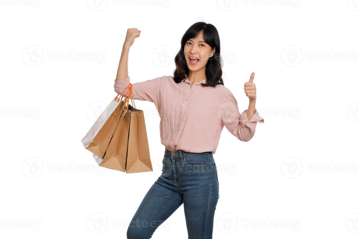 joven contento asiático mujer con casual camisa y mezclilla pantalones participación compras papel bolso aislado en blanco antecedentes foto