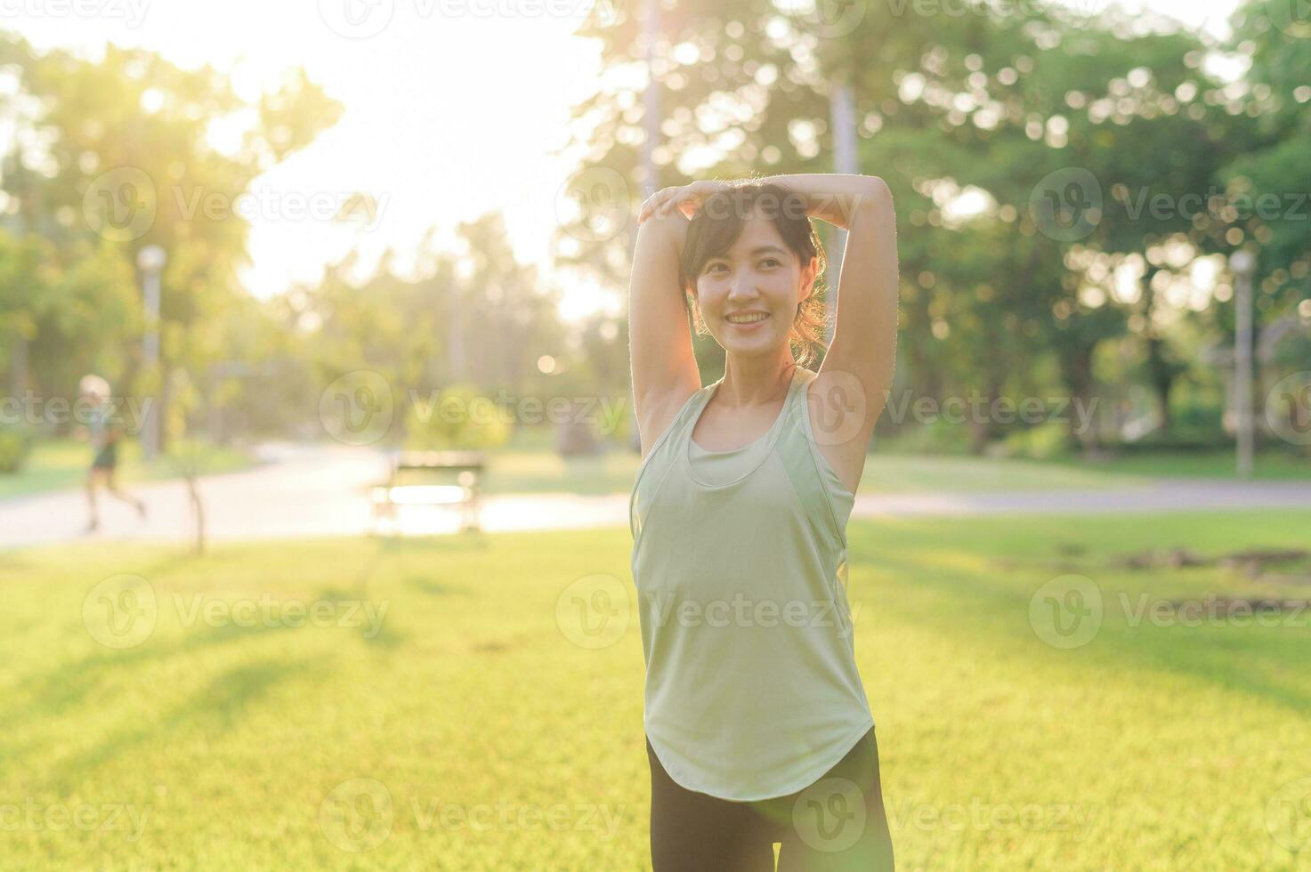 hembra persona que practica jogging. ajuste joven asiático mujer con verde ropa de deporte extensión músculo en parque antes de corriendo y disfrutando un sano exterior. aptitud corredor niña en público parque. bienestar siendo concepto foto