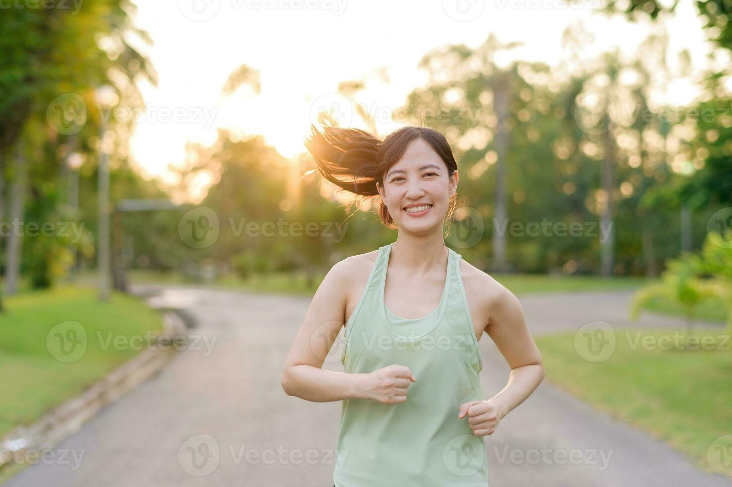 Fit Asian young woman jogging in park smiling happy running and enjoying a healthy outdoor lifestyle. Female jogger. Fitness runner girl in public park. healthy lifestyle and wellness being concept photo
