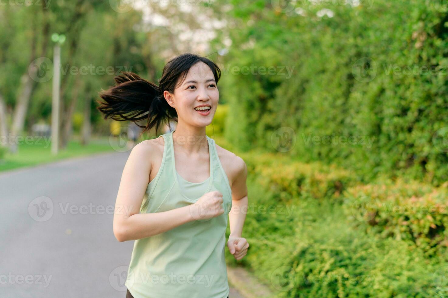 Fit Asian young woman jogging in park smiling happy running and enjoying a healthy outdoor lifestyle. Female jogger. Fitness runner girl in public park. healthy lifestyle and wellness being concept photo