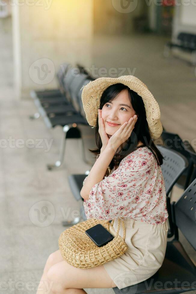joven asiático mujer viajero con Costura cesta esperando para tren en tren estación. viaje viaje estilo de vida, mundo viaje explorador o Asia verano turismo concepto. foto