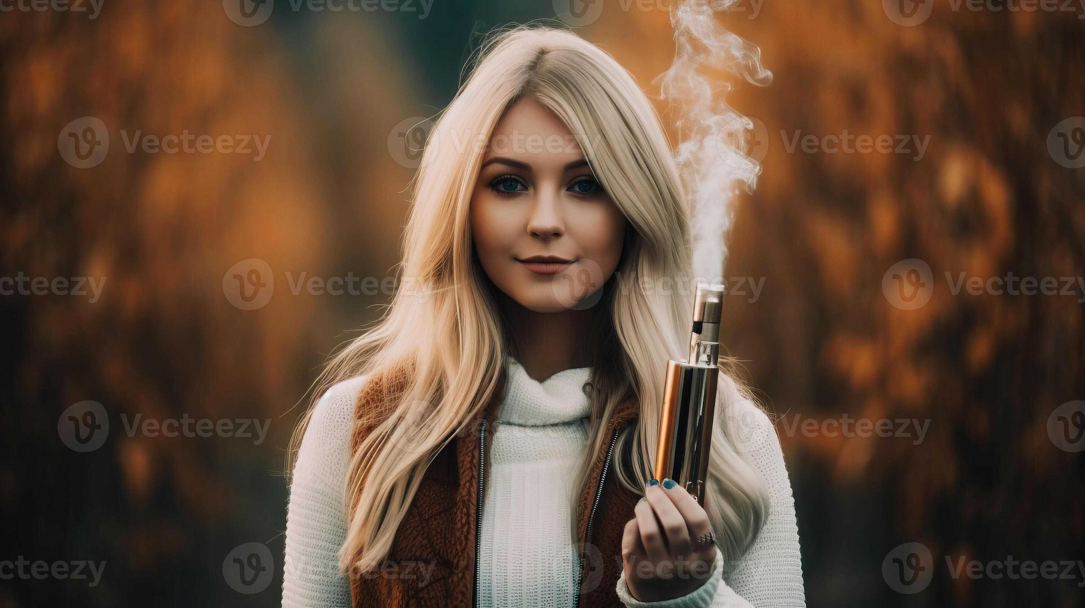 Beautiful young blonde woman smoking electronic cigarette in autumn