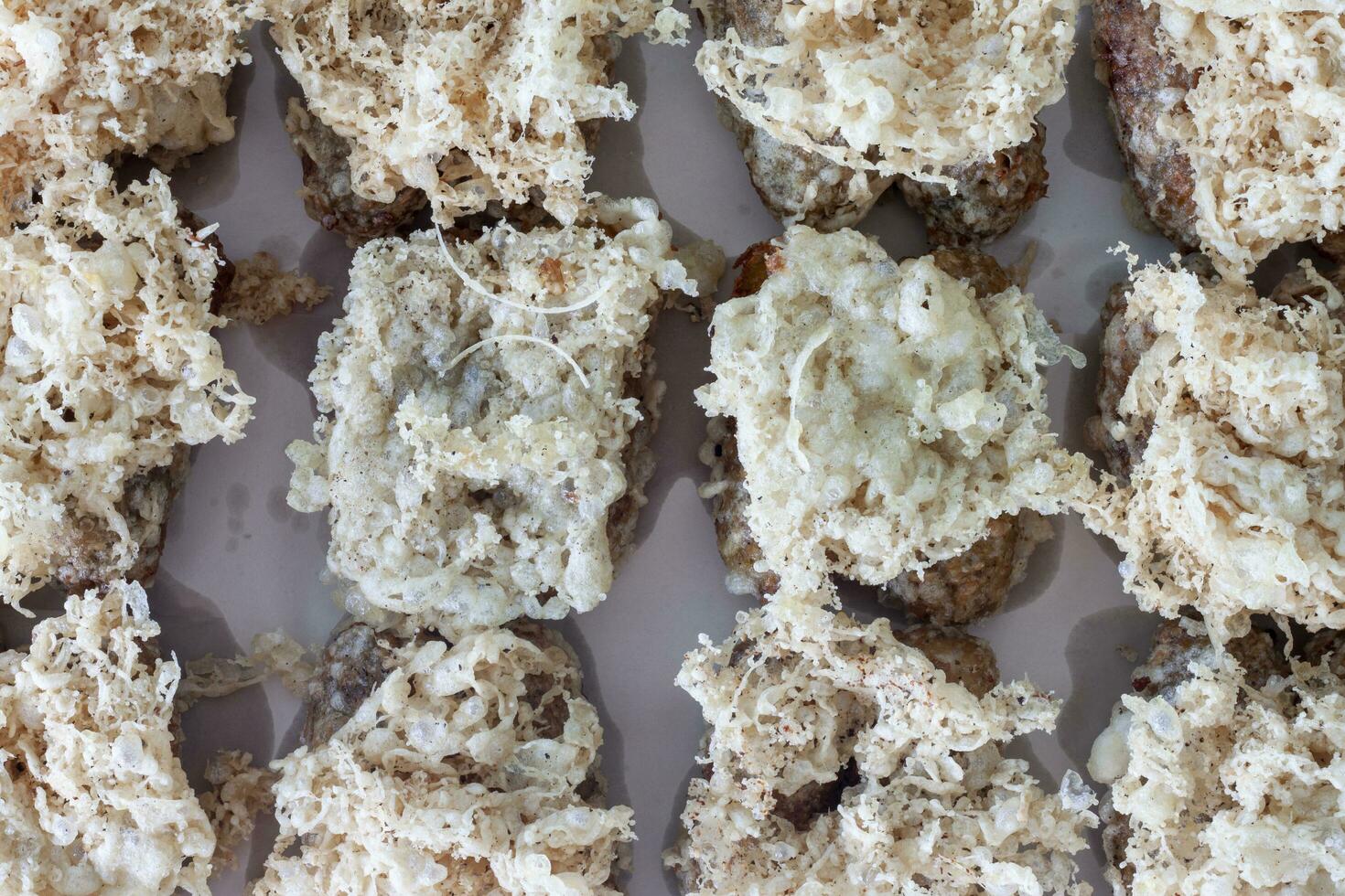 Top view of Thai dessert Khao mao tod. Battered and deep fried unripe rice and grated coconut banana rolls on white blotting paper oil. photo