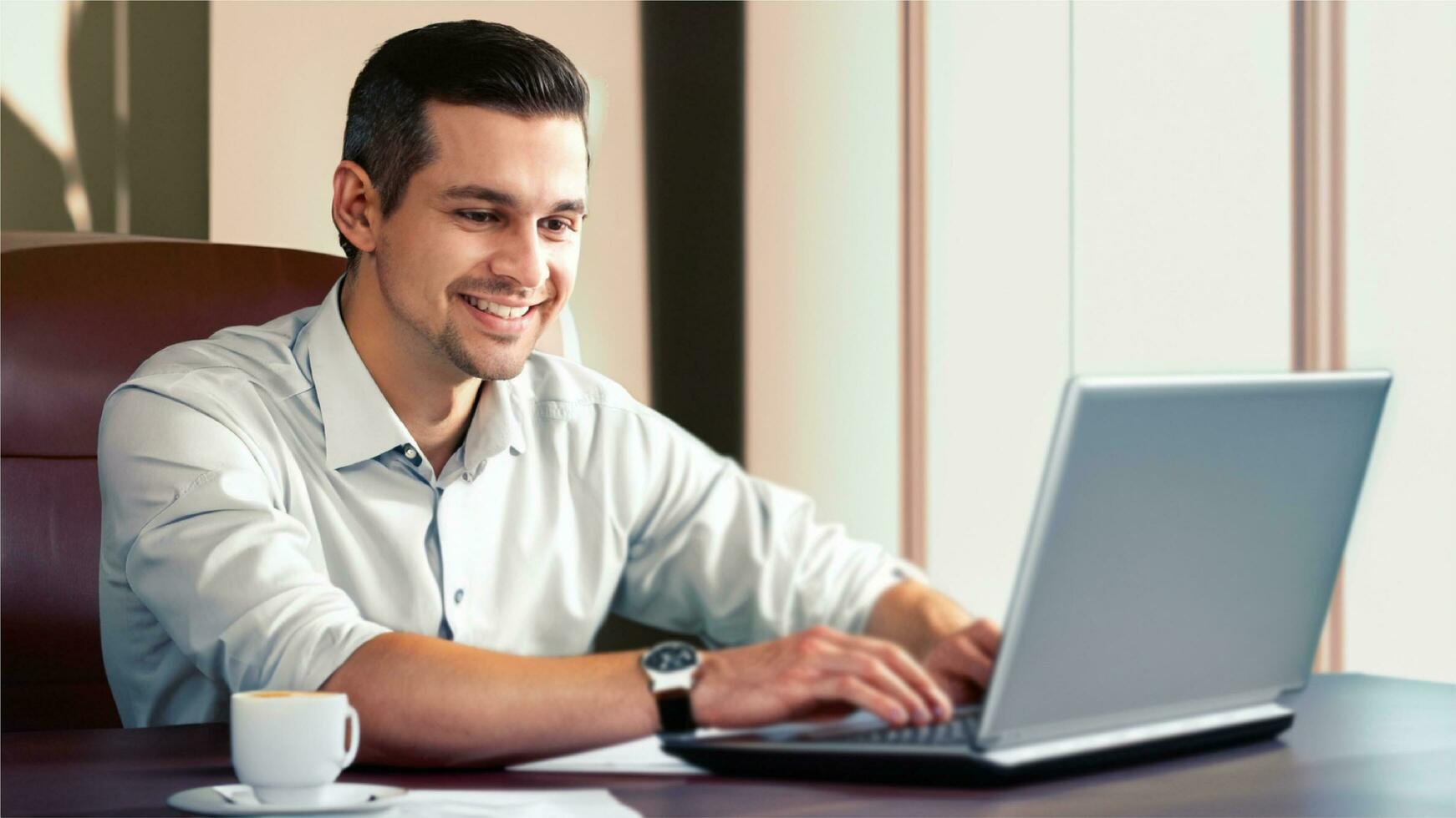 un contento negocio hombre, utilizando computadora portátil, sentado en su oficina escritorio, un taza de té en su mesa, con un Nota libro, un libro estante en esta atrás, realista imagen, alta definición, 4k ultra algunos desenfoque foto