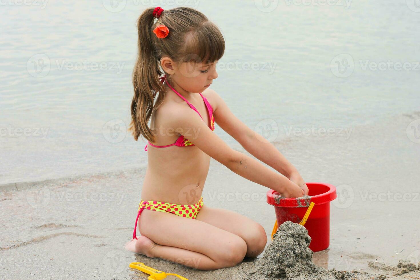 Girl playing with sand on the sea shore photo