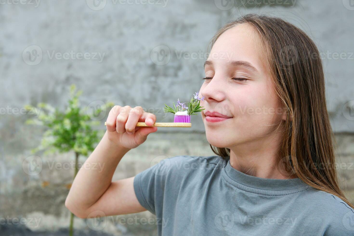 The girl holds a toothbrush with herbed toothpaste with rosemary in her hand. Selective focus on toothbrush and rosemary. photo