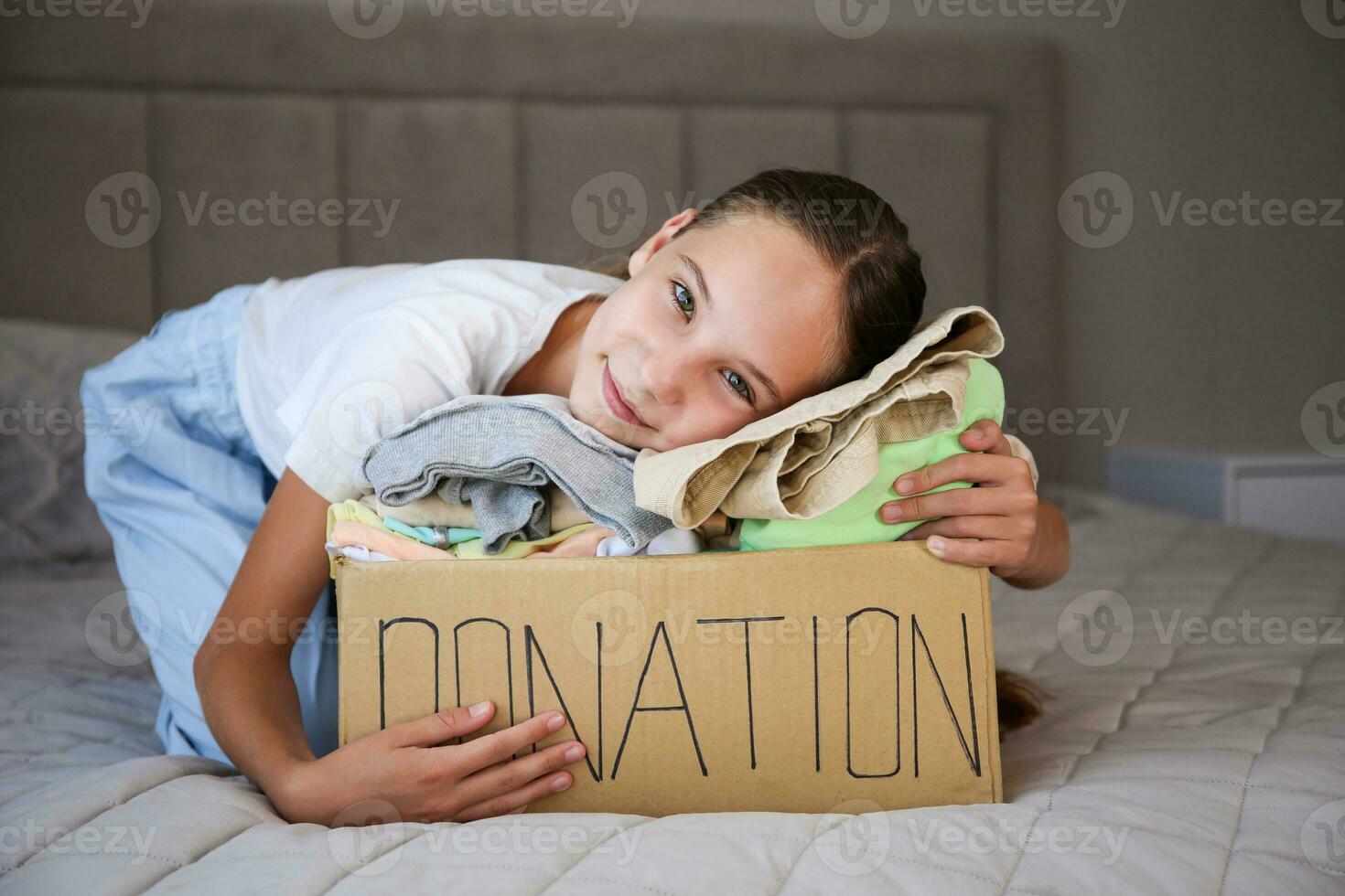 niña participación donación caja con con verano ropa. foto