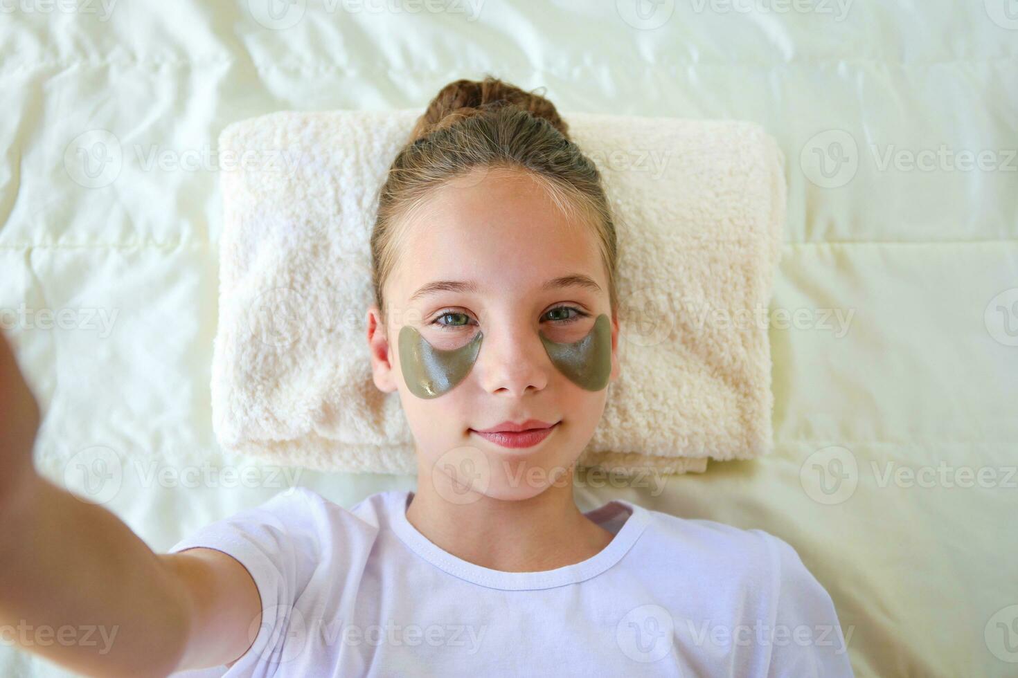 Beautiful girl with hydrogel patches under the eyes taking selfie while posing to phone. photo