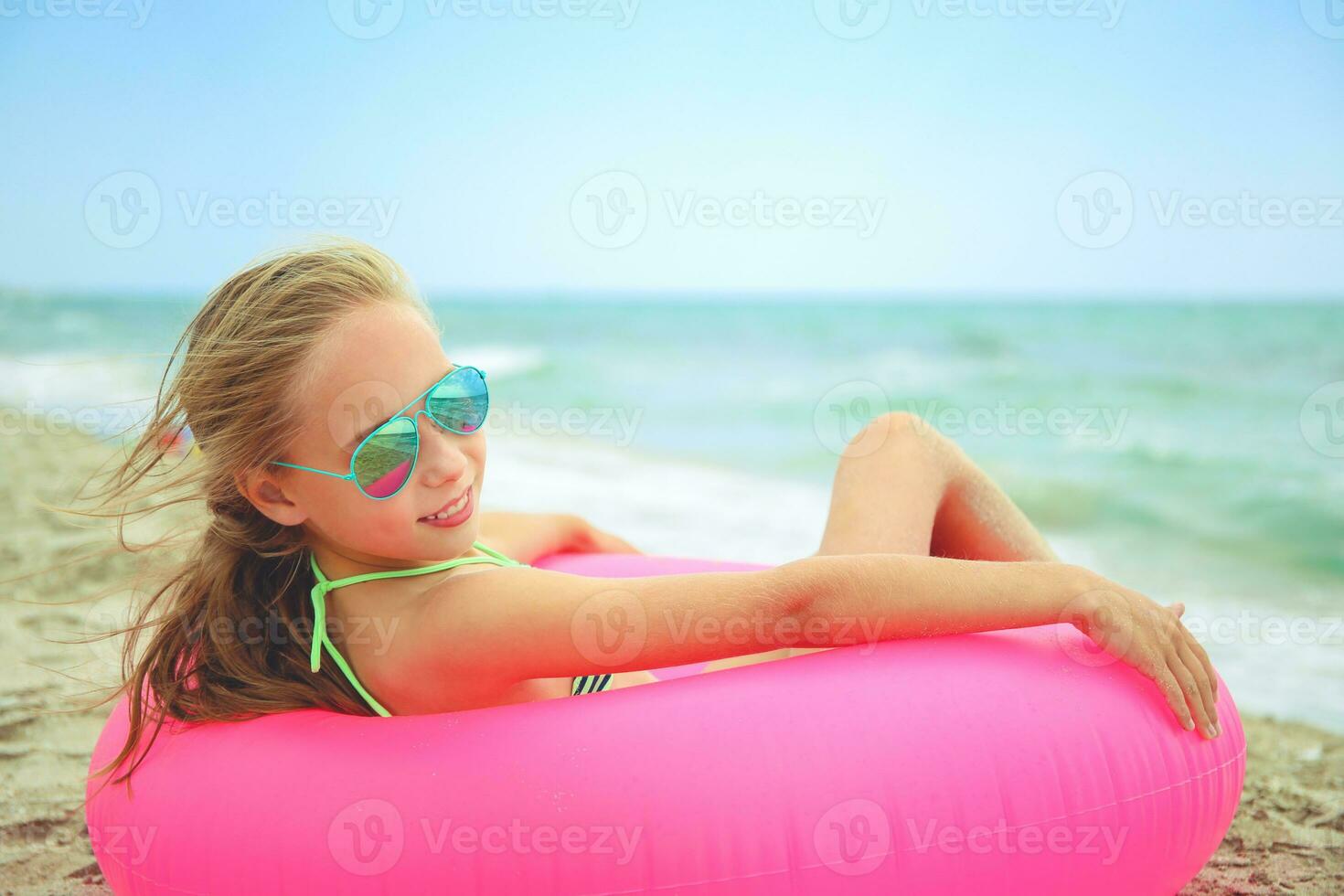 Happy girl lying on pink inflatable circle. Toned image. photo