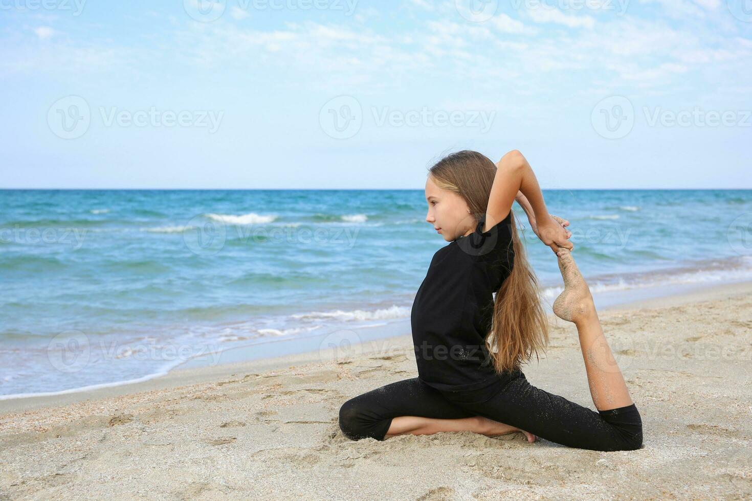 Girl practicing yoga on beach. photo