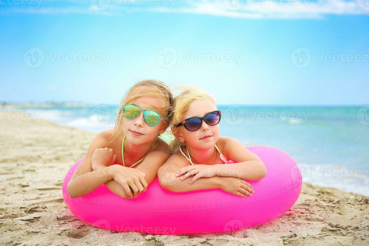 Happy girls lying on pink inflatable circle. photo