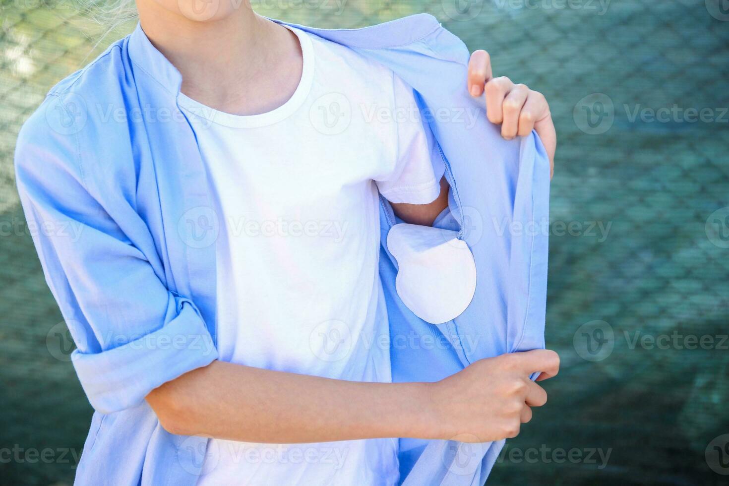 The girl shows a strip of sweat attached to the armpits of shirt. photo