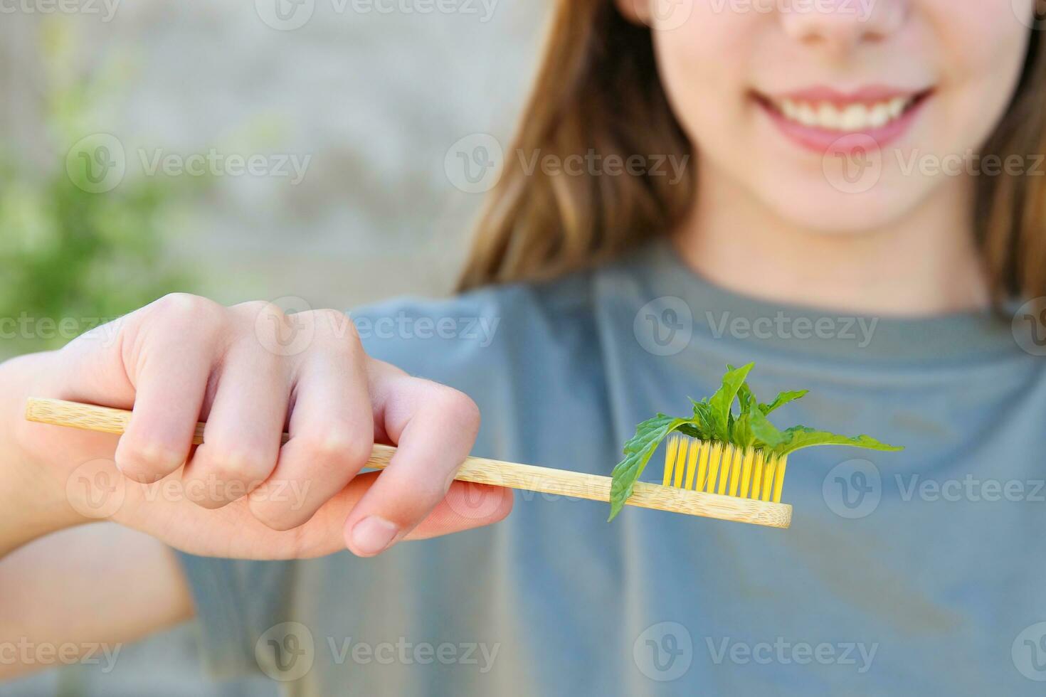 The girl holds a toothbrush with mint in her hand. Selective focus on the mint toothbrush. photo
