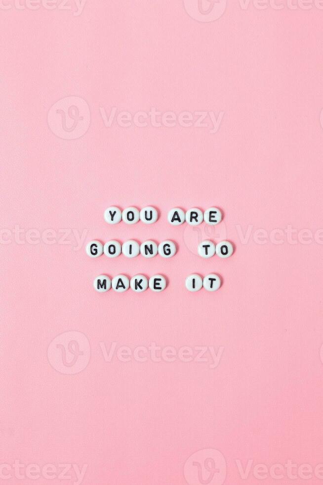 Top view of You are going to make it quotes made out of beads on pastel background. motivation and success concept photo