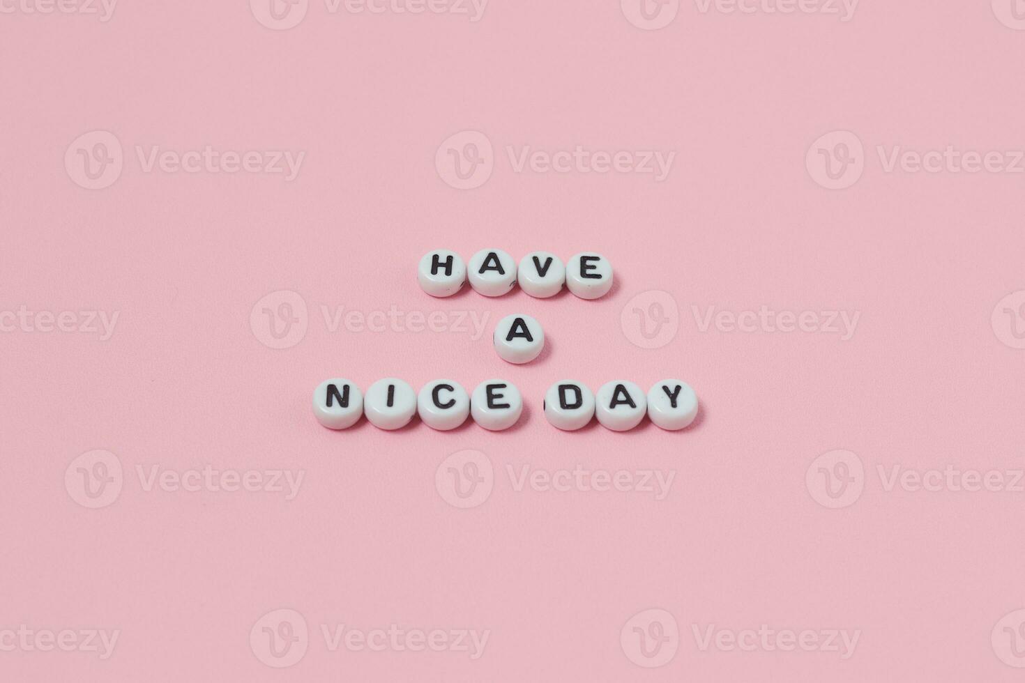 Top view of Have a nice day quotes made out of beads on pink background. motivation and success concept photo