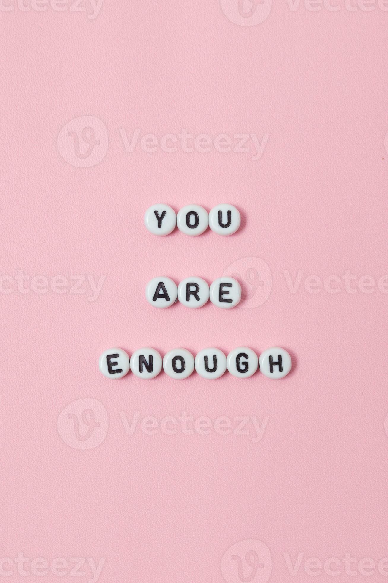 Top view of you are enough quotes made out of beads on pastel