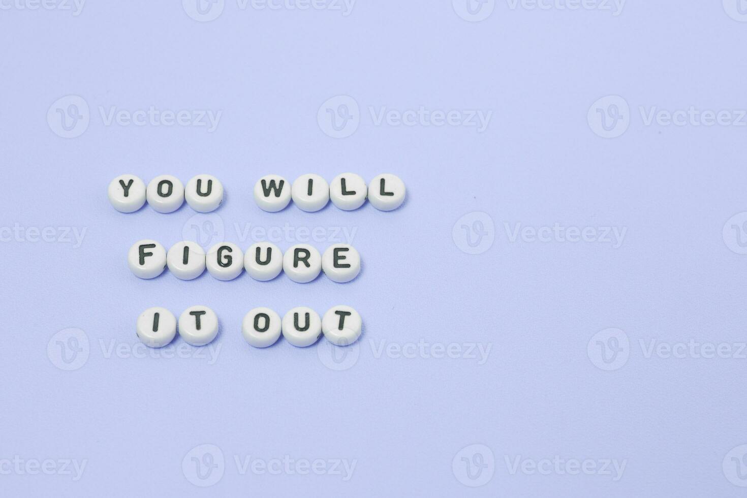 Top view of You will figure it out quotes made out of beads on pastel background. motivation and success concept photo