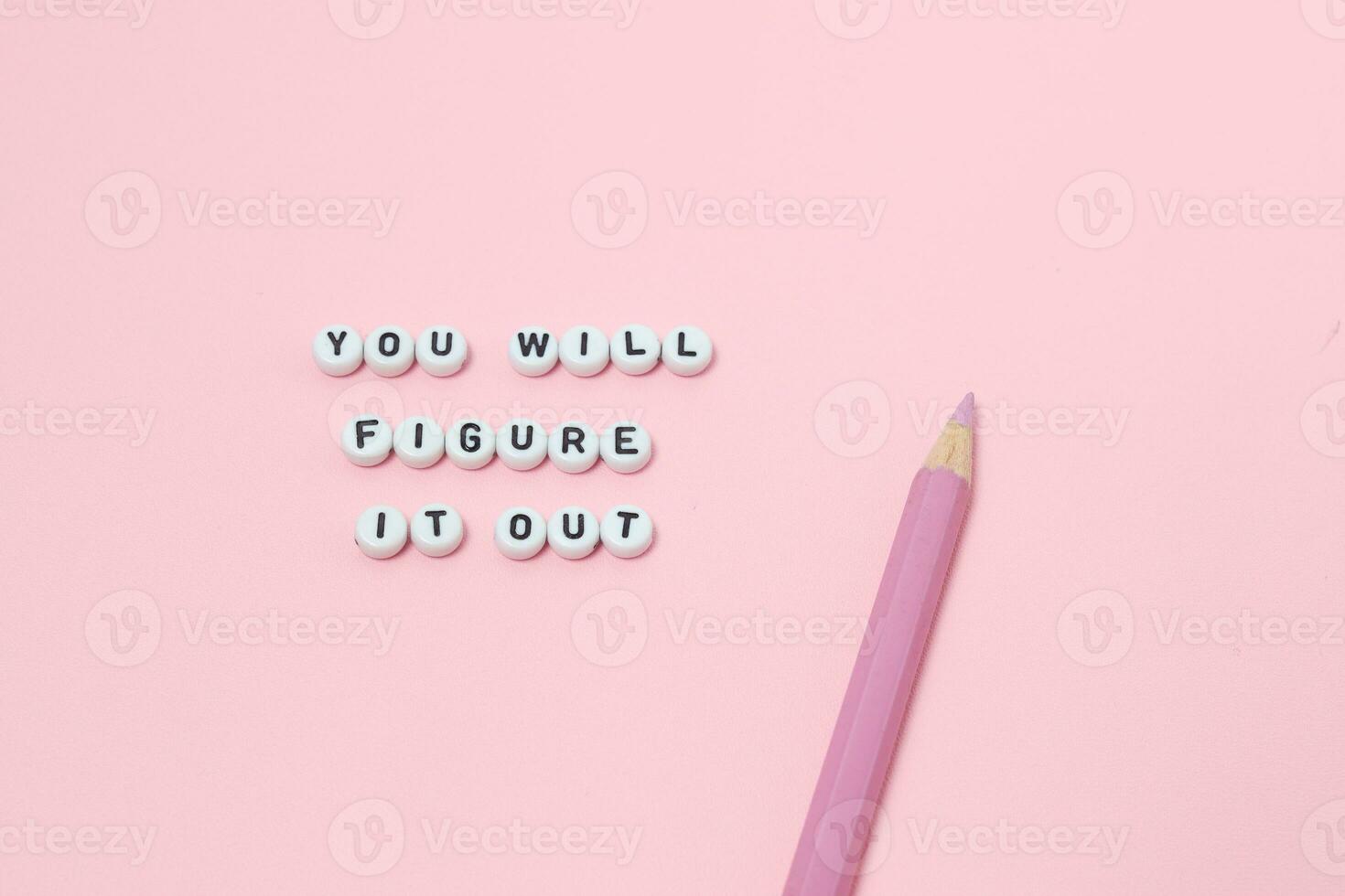 Top view of You will figure it out quotes made out of beads on pastel background. motivation and success concept photo