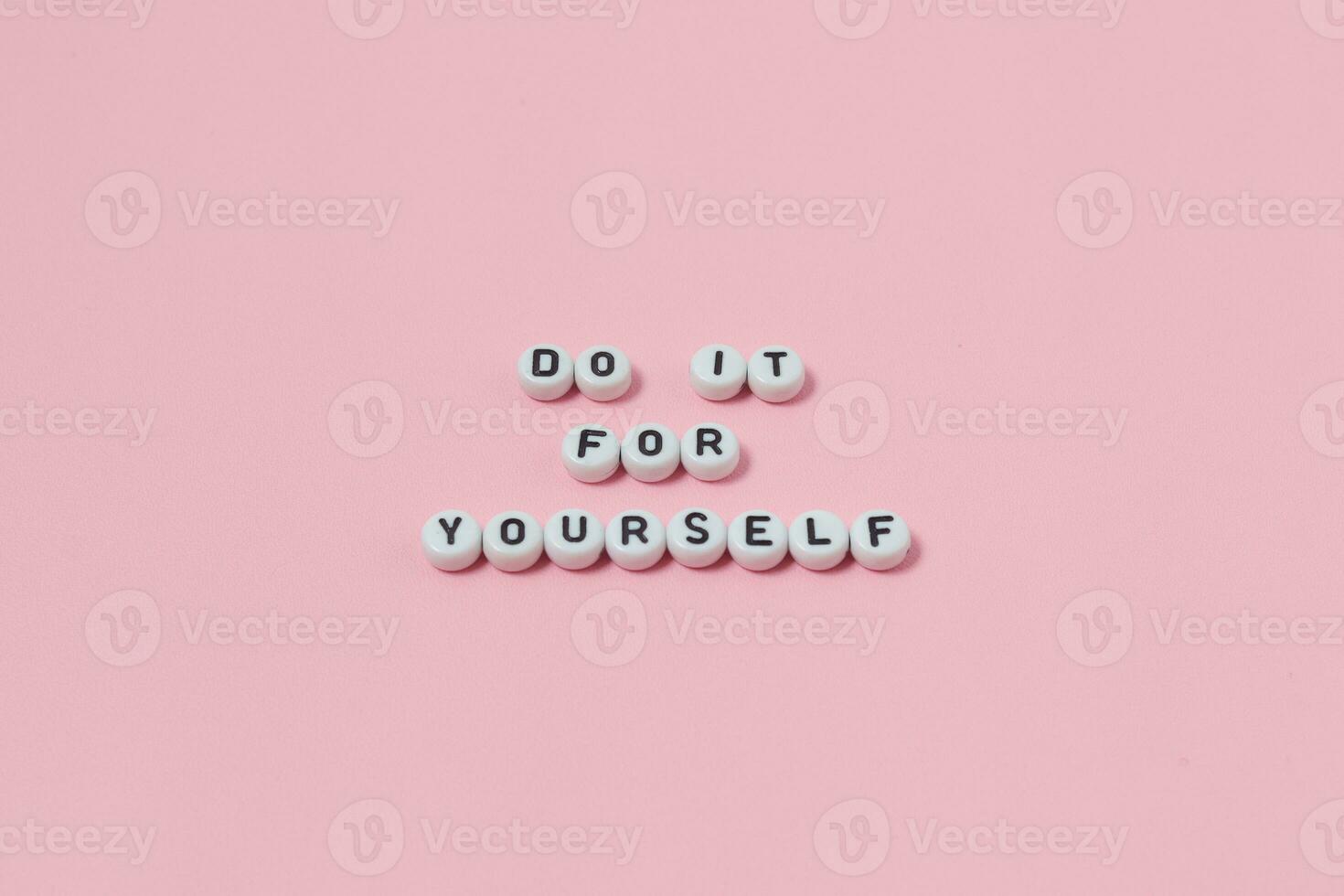 Top view of do it for yourself quotes made out of beads on pink background. motivation and success concept photo