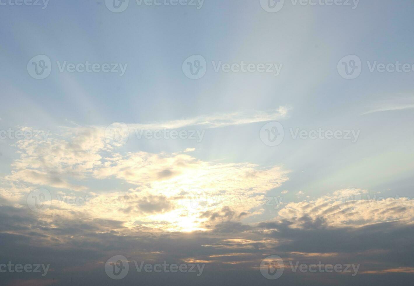 Cloud and sunlight through the cloud with light blue sky, gray cloud at the bottom of pictiure and sun behind the clouds. photo