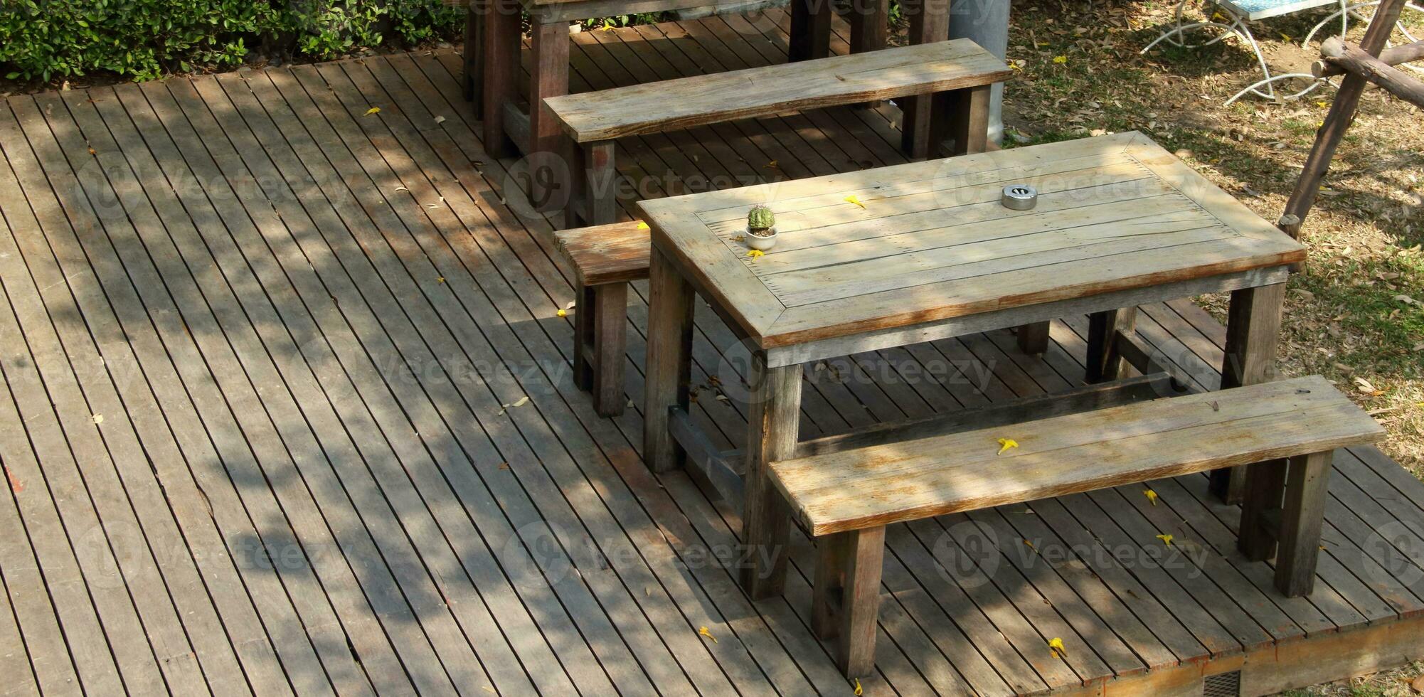 Set of retro style wood table and bench on wood floor outside of building. photo