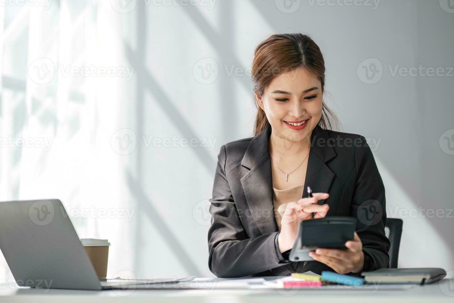 Mujer de negocios que usa la calculadora para hacer finanzas matemáticas en un escritorio de madera en la oficina y el fondo de trabajo empresarial, impuestos, contabilidad, estadísticas y concepto de investigación analítica foto