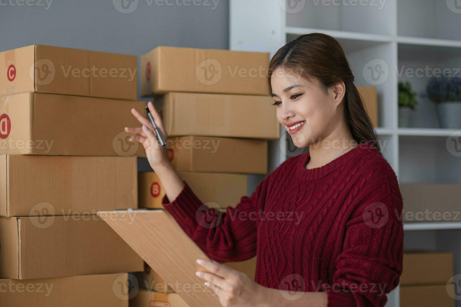 Starting small business entrepreneur of independent Asian woman smiling using computer laptop with cheerful success of online marketing package box items and SME delivery concept photo