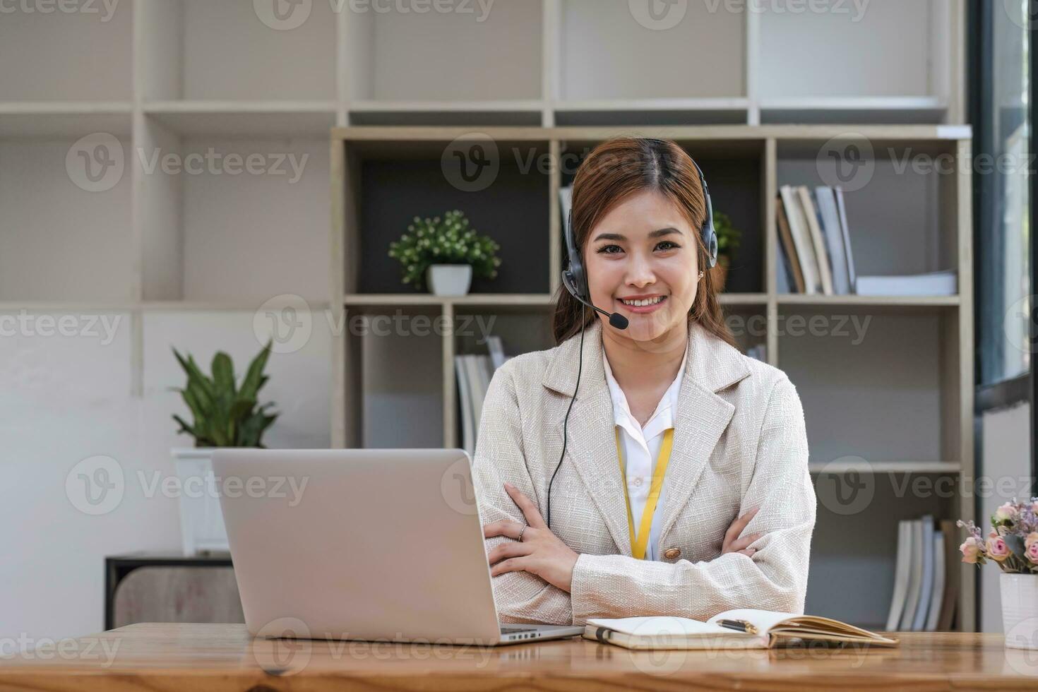 Asian call center with headset and microphone working on her laptop. Female operator provide exceptional customer service. Supportive call center agent helping customer on inquiry. Enthusiastic photo