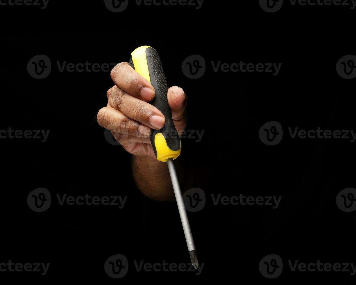 Asian male dark skinned single hand fist finger on black background holding using phillips screwdriver photo