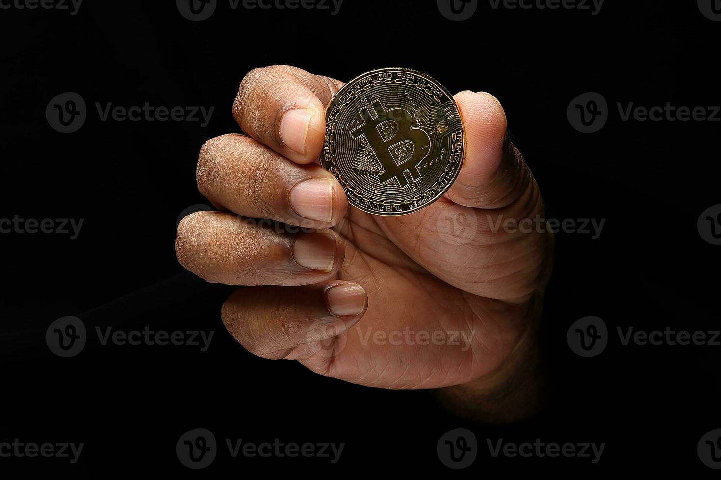 Asian male dark skinned single hand fist finger on black background holding golden fake sample physical bitcoin cryptocurrency photo