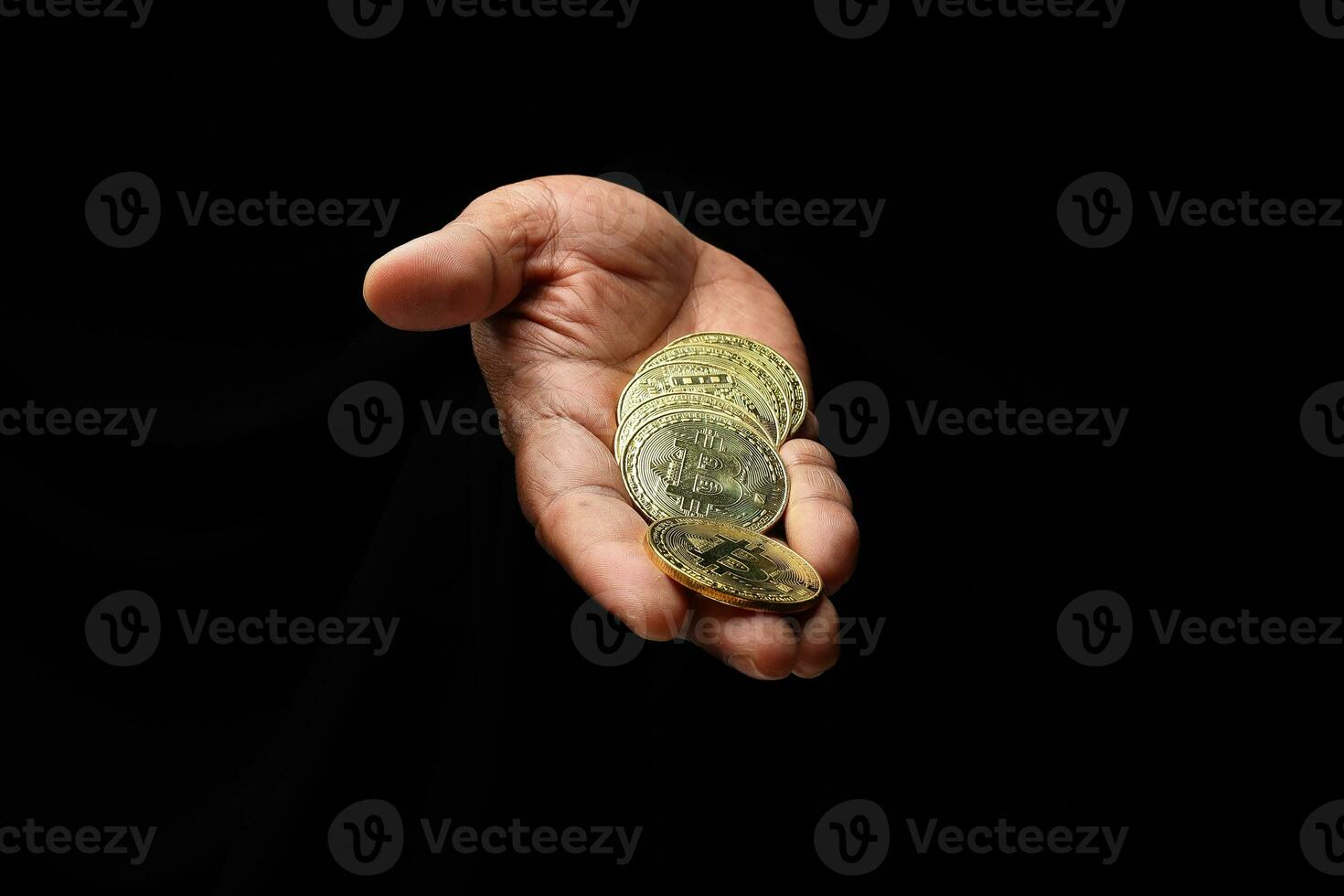 Asian male dark skinned single hand fist finger on black background holding golden fake sample physical bitcoin cryptocurrency photo