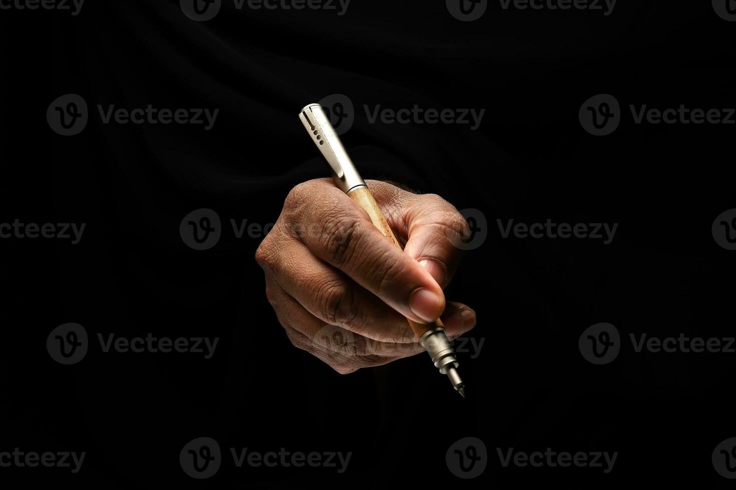 Asian male dark skinned single hand fist finger on black background holding pen write sign photo