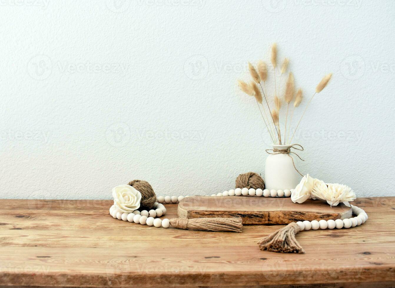 Stylish composition of table with beads and flowers and crown, bench in retro style, clay vases and crockery. Rustic inspiration. Summer vibes. Beige wood table. photo