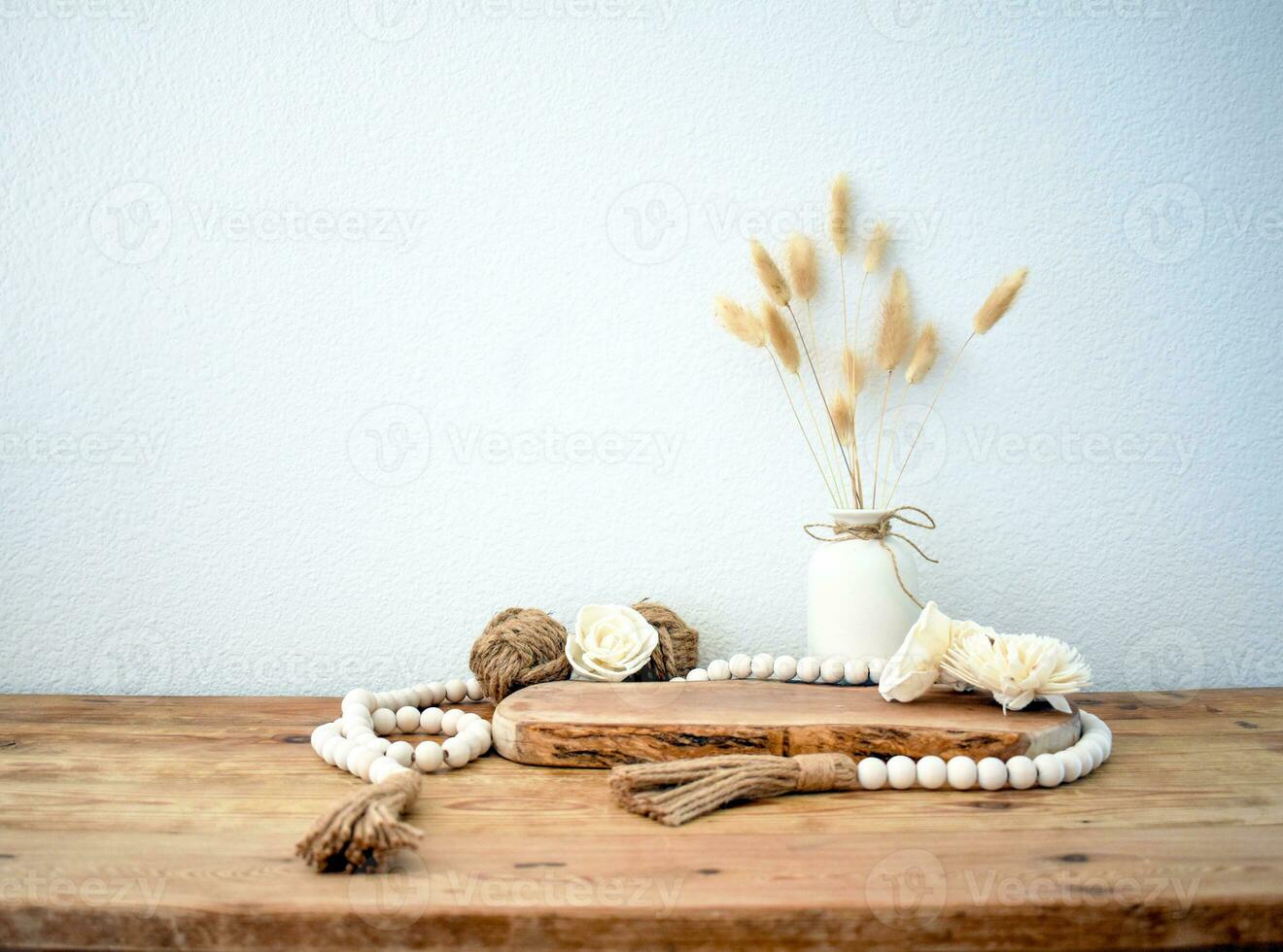 Stylish composition of table with beads and flowers and crown, bench in retro style, clay vases and crockery. Rustic inspiration. Summer vibes. Beige wood table. photo