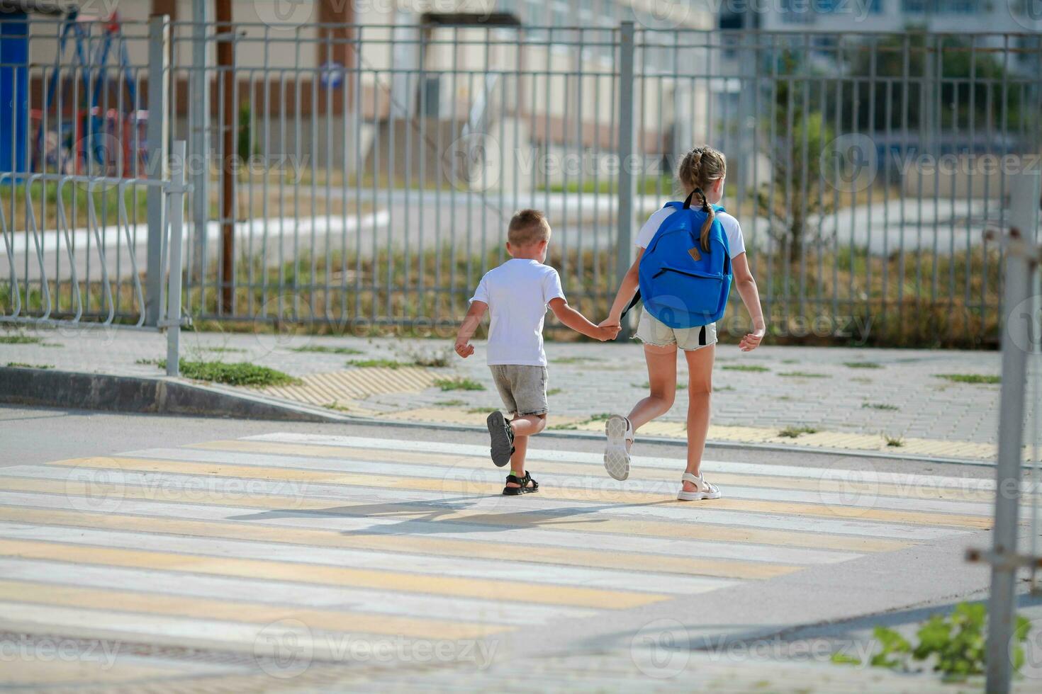 Brother and sister run across a pedestrian crossing. Children Run along the road to kindergarten and school.Zebra traffic walk way in the city. Concept pedestrians passing a crosswalk photo