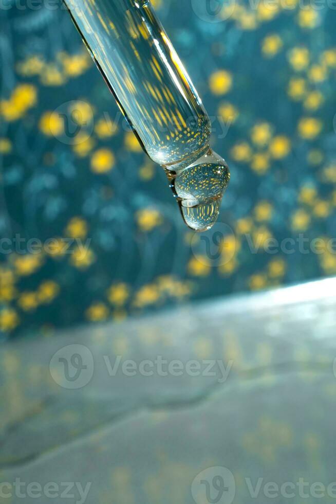 A dripping pipette with a drop of cosmetics gel. photo