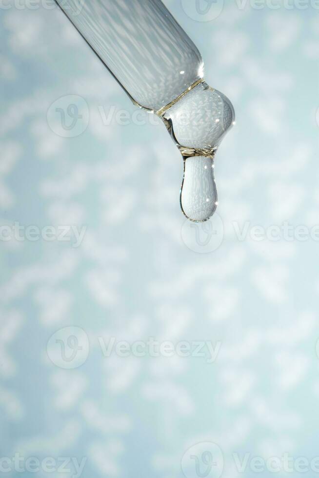 A dripping pipette with a drop of cosmetics gel. photo