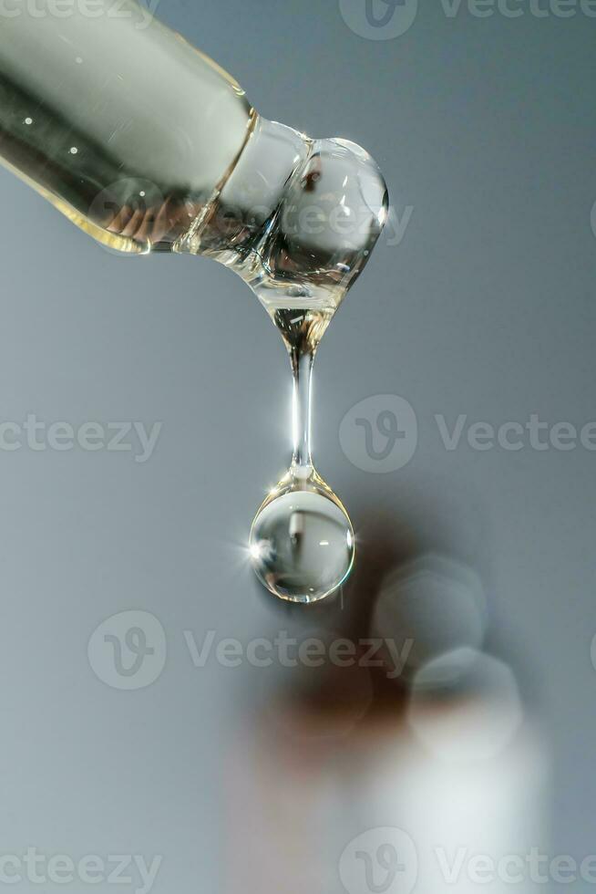 Cosmetic pipette with a drop on dark background. photo