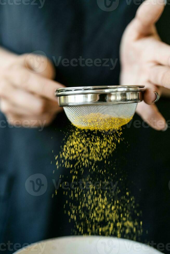 The girl sifts turmeric into a bowl. photo