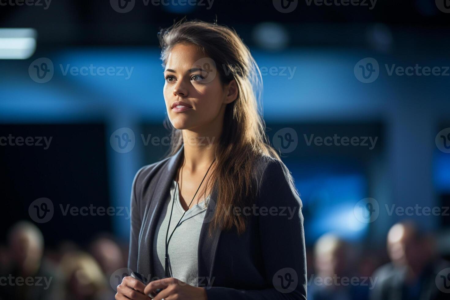 young woman giving a talk at a conference in a bright stage with photo