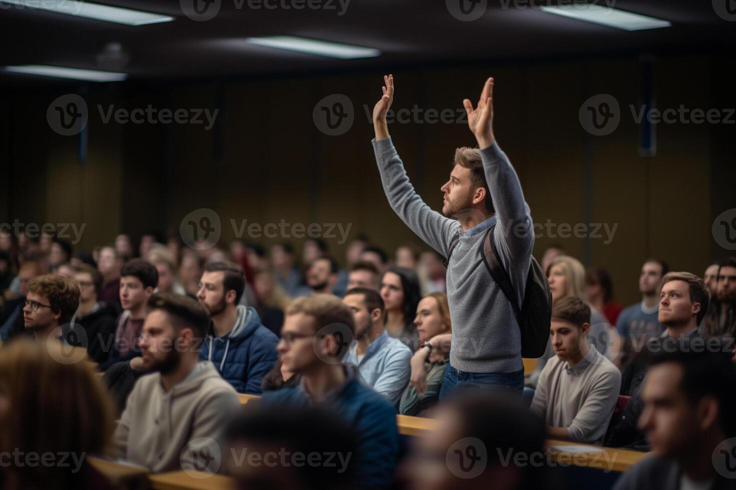 a male student raising hands at a lecture theatre with photo