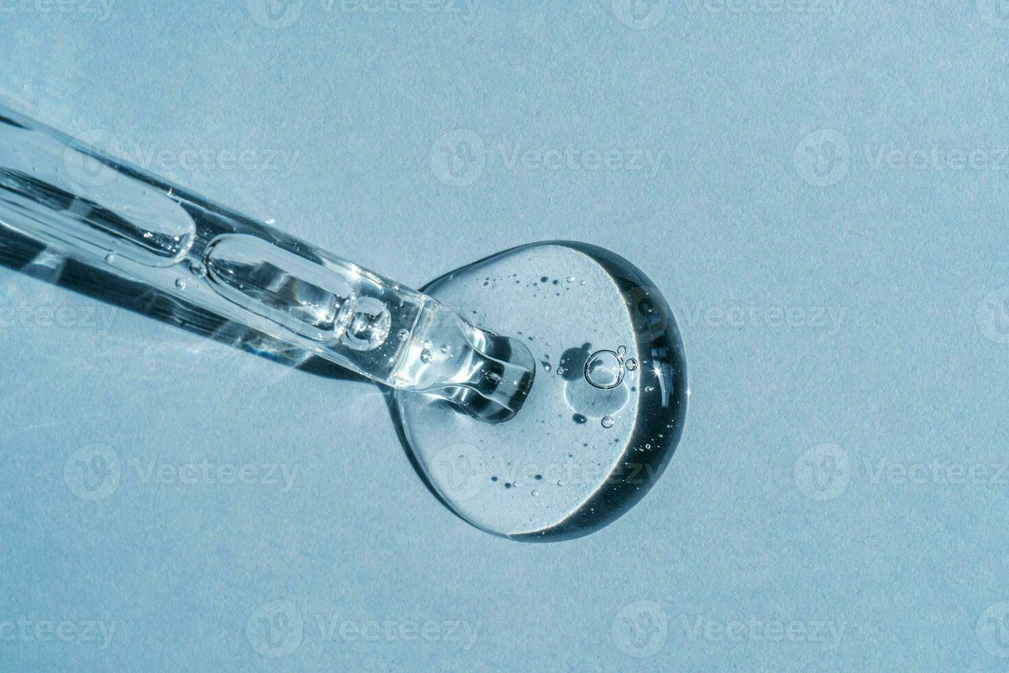 A cosmetic product on a blue background flows out of a pipette with bubbles photo
