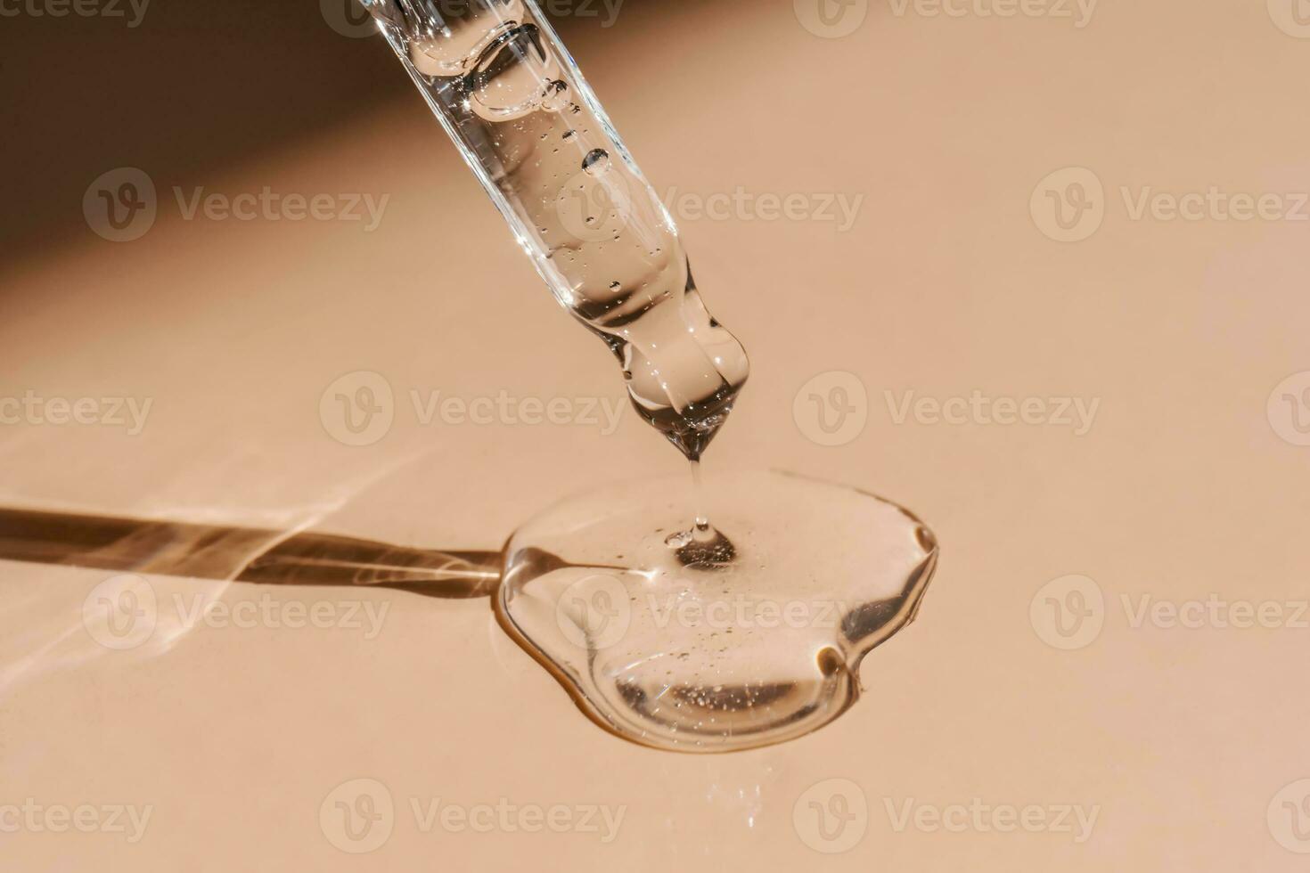 A drop of cosmetic oil falls from the pipette photo