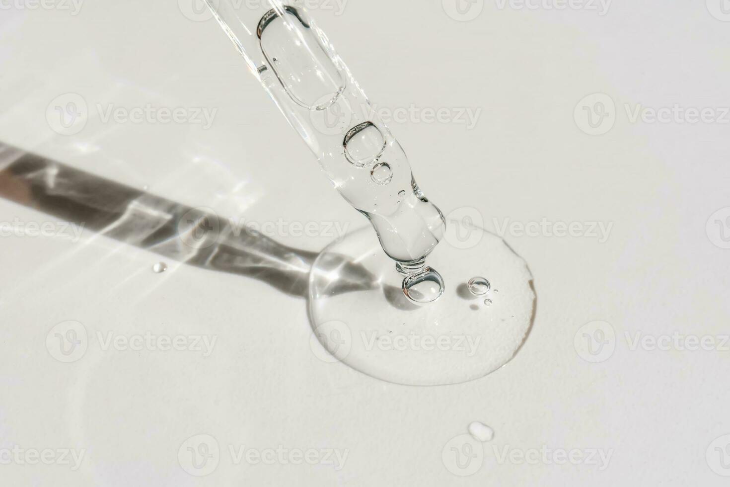 A drop of cosmetic oil falls from the pipette photo